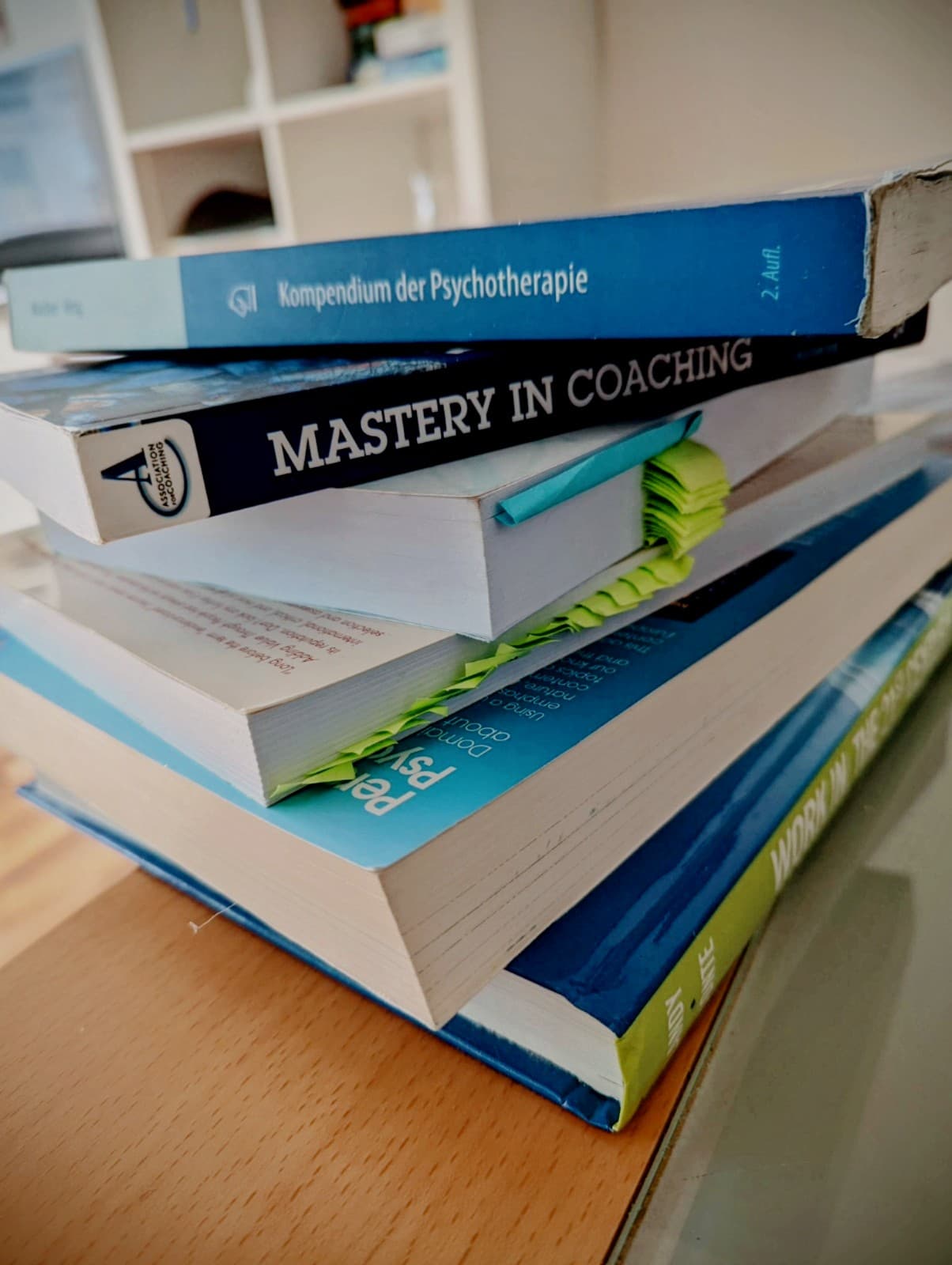 Stapel von Fachbüchern über Psychotherapie und Coaching mit vielen bunten Markierungen auf einem hellen Tisch.
